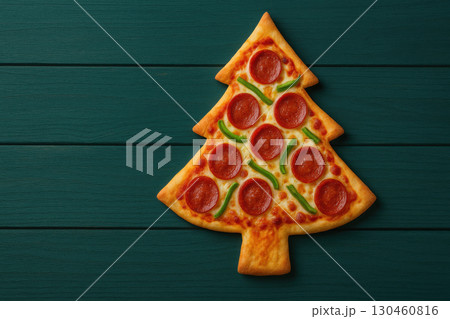 Creative Christmas pizza shaped like tree, topped with pepperoni and green peppers, resting deep teal wooden table, perfect for holiday 130460816