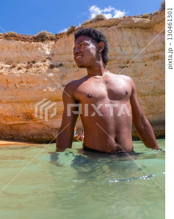 Young African American man swims in ocean in Algarve Portugal Sea da Rocha Beach Young African American man swims in ocean in Algarve Portugal Sea da Rocha Beach 130461301