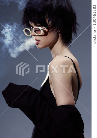 Stylish woman with short hair wearing sunglasses and smoking, dressed in black with moody lighting and smoke detail Stylish woman with short hair wearing sunglasses and smoking, dressed in black with moody lighting and smoke detail 130461583