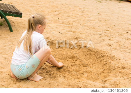8 year old girl playing with sand on the beach 130461806