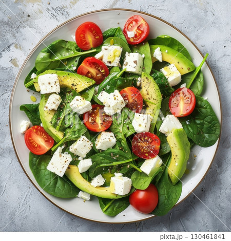 Realistic healthy salad with avocado, spinach, cherry tomatoes, feta cheese, flat lay on light stone background, natural light from side, food photography AI generated 130461841