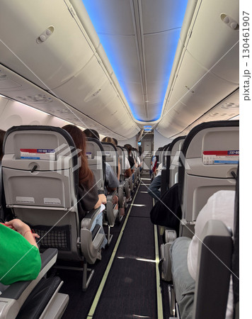 Inside view of airplane cabin with passengers seated during flight. Travel experience, aviation comfort and in-flight atmosphere of commercial airline journey. Inside view of airplane cabin with passengers seated during flight. Travel experience, aviation comfort and in-flight atmosphere of commercial airline journey. 130461907