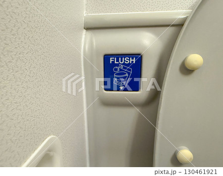 Flush button inside airplane lavatory. Aviation design, hygiene, and passenger facilities onboard. 130461921