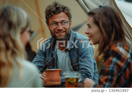 A joyful gathering of friends enjoying drinks around a campfire, sharing stories and laughter in a cozy outdoor setting. A joyful gathering of friends enjoying drinks around a campfire, sharing stories and laughter in a cozy outdoor setting. 130461987