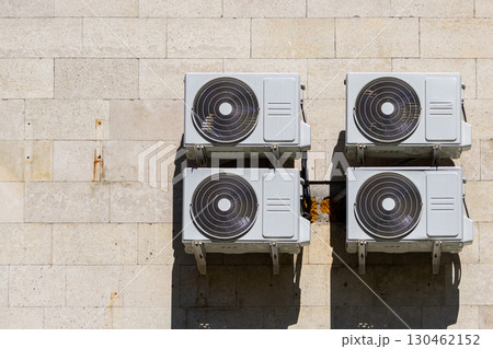 Four air conditioners are mounted on the wall. air conditioners are white. Four air conditioners are mounted on the wall. air conditioners are white. 130462152