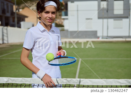 Young Tennis Player Posing on Outdoor Court Holding Racket and Ball Young Tennis Player Posing on Outdoor Court Holding Racket and Ball 130462247