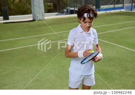Young Tennis Player Preparing Ball and Racket on Sunny Outdoor Court Young Tennis Player Preparing Ball and Racket on Sunny Outdoor Court 130462248