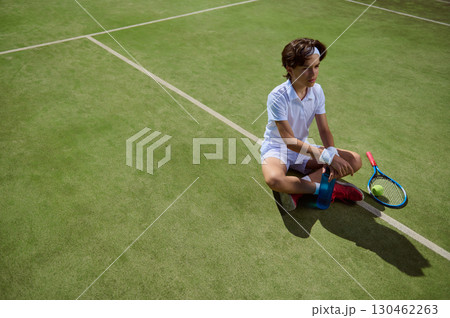 Young Tennis Athlete Resting on Court with Racket and Water Bottle Young Tennis Athlete Resting on Court with Racket and Water Bottle 130462263