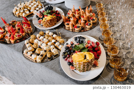 Elegant catering table with assorted canapes, fresh fruits and whiskey glasses 130463019