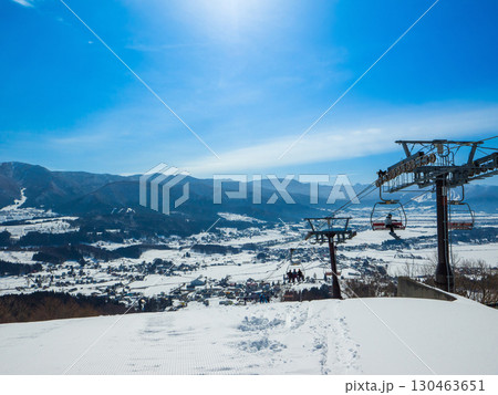 太陽が輝く青空とスキー場から望む雪国の風景 (長野県、飯山市、戸狩温泉) 130463651