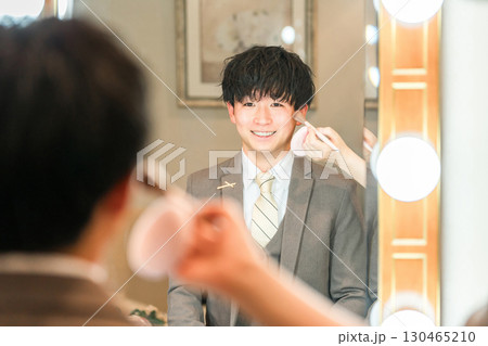 結婚式場のブライズルームでメイクをするスーツ,タキシード姿の新郎 130465210