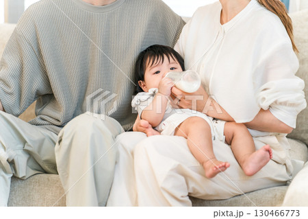 マイホームのソファーで赤ちゃんに哺乳瓶でミルクを飲む赤ちゃん,乳幼児 マイホームのソファーで赤ちゃんに哺乳瓶でミルクを飲む赤ちゃん,乳幼児 130466773