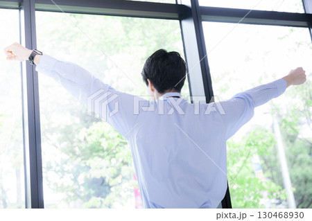窓際でストレッチする深呼吸で休憩するビジネスマン　顔無しの後ろ姿 130468930