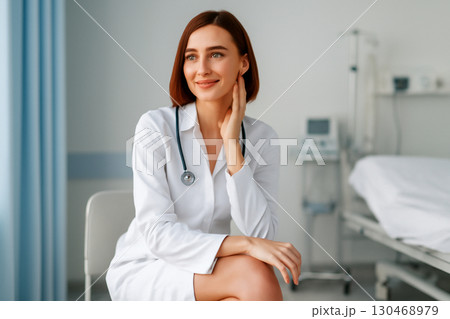 AI generated ultra-realistic portrait of a confident female doctor in a medical clinic. Warm, inviting smile and modern healthcare setting with soft lighting and minimal design. AI generated ultra-realistic portrait of a confident female doctor in a medical clinic. Warm, inviting smile and modern healthcare setting with soft lighting and minimal design. 130468979