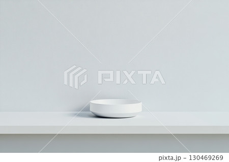 Simple white bowl on a minimalistic shelf against a clean, muted wall 130469269