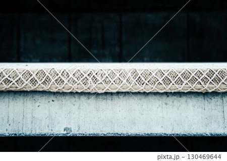 Artistic close-up of a textured rope placed on a concrete surface showcasing unique patterns during daylight 130469644