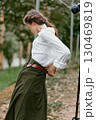 Elegant outdoor portrait of a female model wearing a white blouse and green skirt, showcasing natural beauty and emotional expressiveness in a serene garden background 130469819