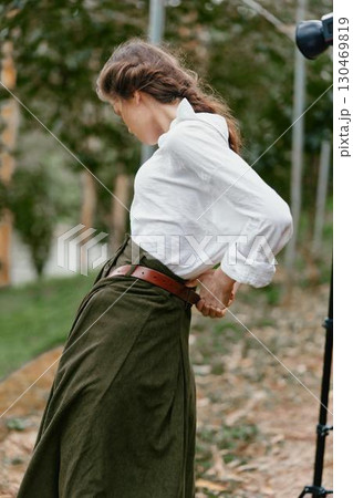 Elegant outdoor portrait of a female model wearing a white blouse and green skirt, showcasing natural beauty and emotional expressiveness in a serene garden background Elegant outdoor portrait of a female model wearing a white blouse and green skirt, showcasing natural beauty and emotional expressiveness in a serene garden background 130469819
