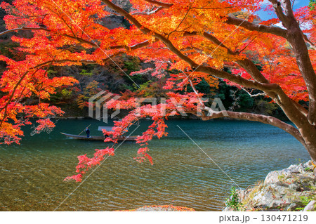 Boatman punting tourist boat along Arashiyama river in autumn 130471219