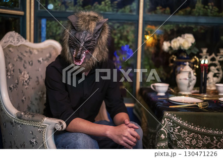 man with werewolf mask at dinner table for 2025 Halloween party 130471226