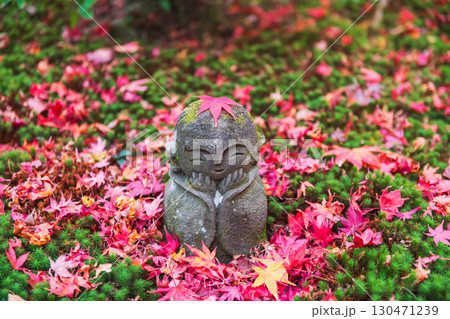 Smiling Jizo with fallen red autumn maple leaf at Enkoji garden, Kyoto 130471239