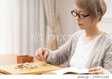 1人で趣味の将棋の練習をするシニア女性 1人で趣味の将棋の練習をするシニア女性 130471288