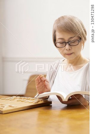 1人で趣味の将棋の練習をするシニア女性 130471298