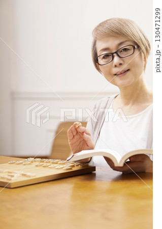 1人で趣味の将棋の練習をするシニア女性 1人で趣味の将棋の練習をするシニア女性 130471299