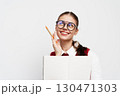 Smiling student with glasses holding a notebook and a pencil, looking thoughtful against a white background Engaging expression indicating creativity and inspiration 130471303