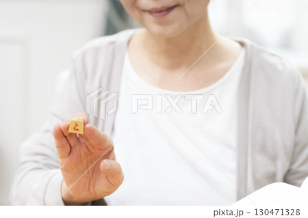 1人で趣味の将棋の練習をするシニア女性の手元 130471328