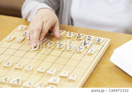 1人で趣味の将棋の練習をするシニア女性の手元 130471332