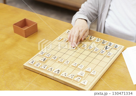 1人で趣味の将棋の練習をするシニア女性の手元 130471334