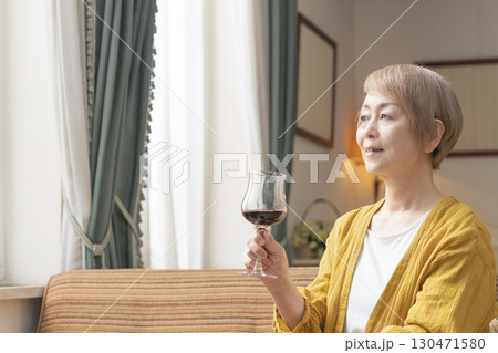 リビングでワインを飲んでくつろぐシニア女性 リビングでワインを飲んでくつろぐシニア女性 130471580
