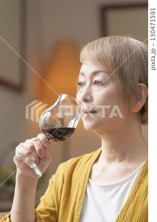 リビングでワインを飲んでくつろぐシニア女性 リビングでワインを飲んでくつろぐシニア女性 130471591