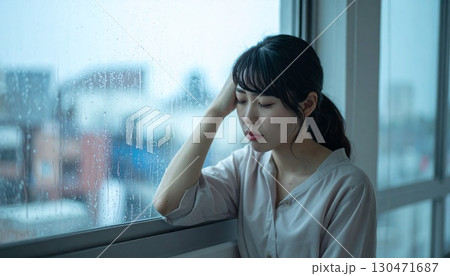 雨の日に窓辺で頭を抱える女性 130471687