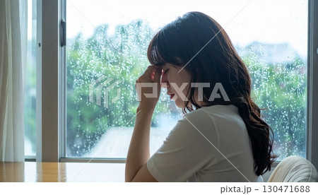 窓の外の雨を背に思い悩む女性の姿 130471688