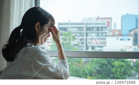 憂うように目を閉じる雨の日の女性 130471690
