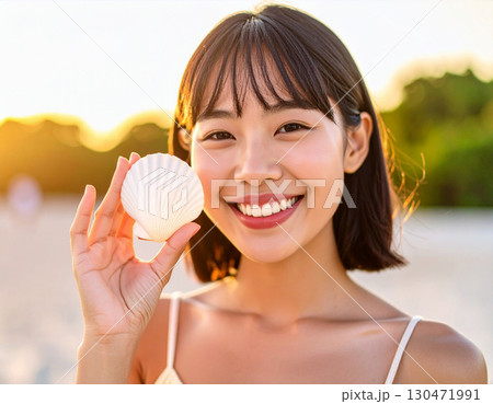 砂浜で貝殻を集める若い女性/ Young woman collecting seashells on 130471991
