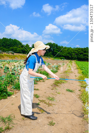 高原で虫取り網を持つ麦わら帽子の女の子　夏の自然体験 130473317