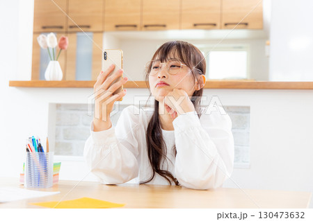 スマホを見ながら考える女性 130473632