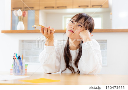 スマホを見ながら考える女性 130473633