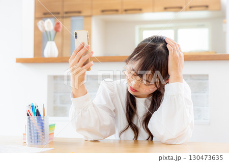 スマホを見ながら考える女性 130473635