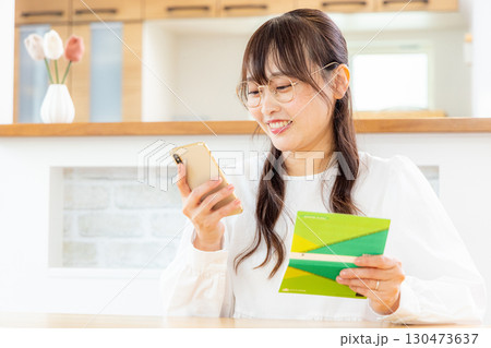 スマホと家計簿をつける女性 スマホと家計簿をつける女性 130473637