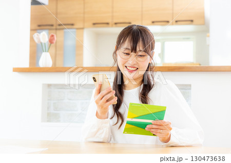 スマホと家計簿をつける女性 スマホと家計簿をつける女性 130473638