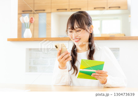 スマホと家計簿をつける女性 130473639