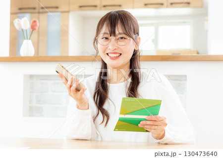 スマホと家計簿をつける女性 130473640