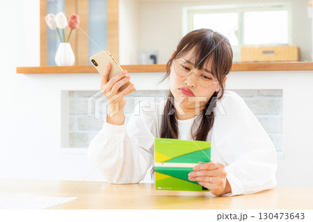 預金通帳を見て悩む女性 130473643