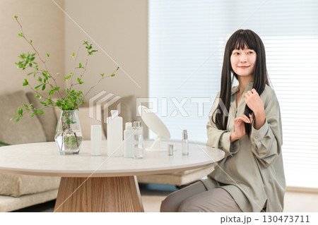 自宅のリビングでヘアケアをする若いアジア人女性 自宅のリビングでヘアケアをする若いアジア人女性 130473711
