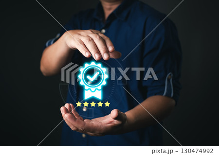 A person in a dark blue shirt presents a glowing certificate icon with a checkmark and five stars, symbolizing quality assurance and trust in digital standards, service, or performance. A person in a dark blue shirt presents a glowing certificate icon with a checkmark and five stars, symbolizing quality assurance and trust in digital standards, service, or performance. 130474992