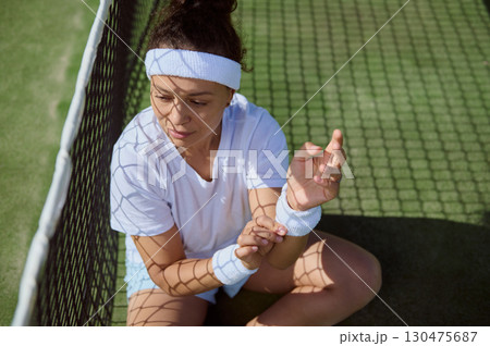 Young Woman Resting on Tennis Court in Sunlight 130475687